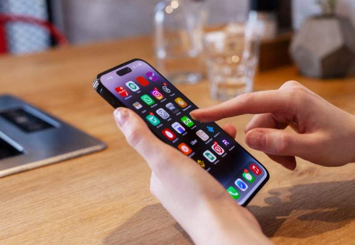 2446621625 featured image Person using smartphone with colorful app icons displayed