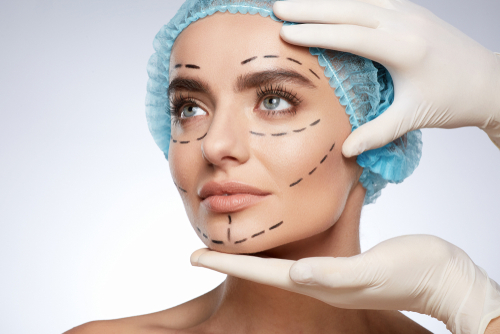 plastic surgery_795630106.jpg featured image Woman with surgical markings on face wearing cap