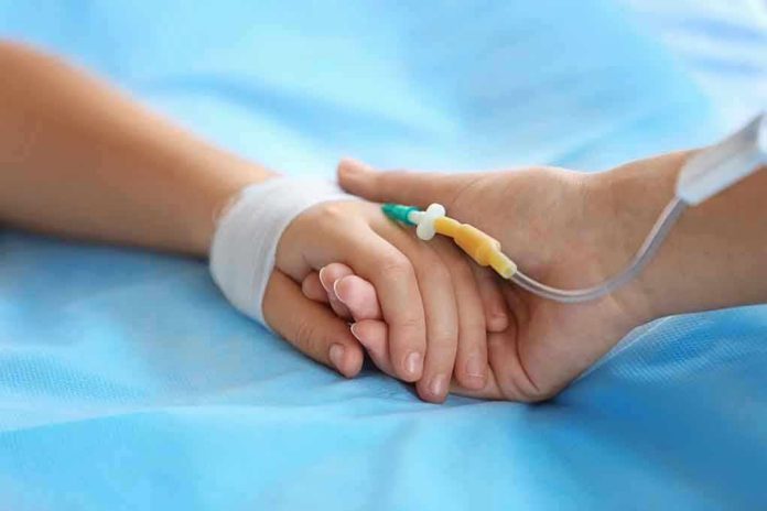 531203017 Two hands holding, one with medical IV attached.