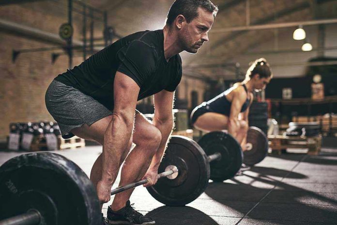 791792701 Man and woman lifting barbells in gym.