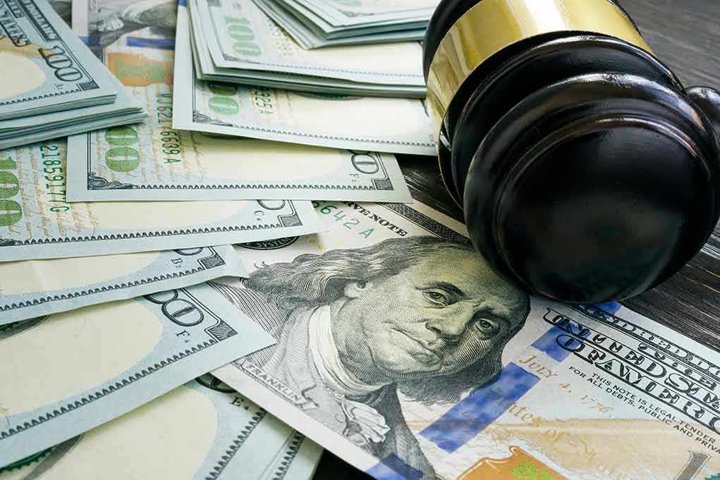 Gavel and hundred dollar bills on table
