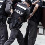 Police officers arresting a handcuffed person