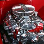 Close up of a shiny chrome engine inside a red car