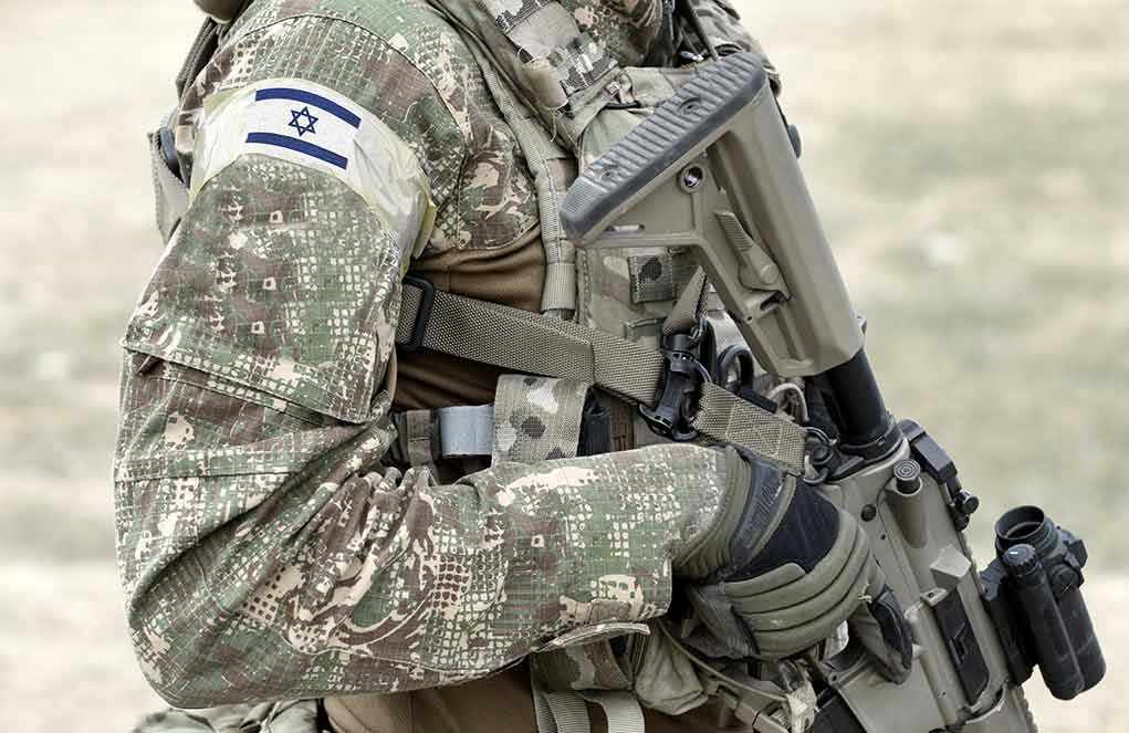 1917131027 Soldier in camouflage gear with Israeli flag patch.
