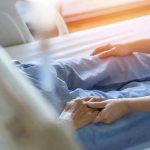 Hospital patient holding visitors hand reassuringly