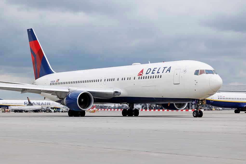 2305553471 Delta Airlines airplane on airport runway, cloudy sky.