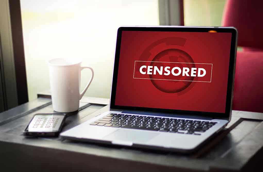 613288766 Laptop screen displaying CENSORED beside coffee and phone