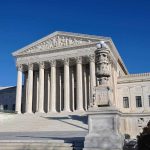 The Supreme Court building with large columns and a clear blue sky