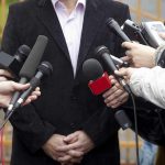 A group of microphones surrounding a person at a press conference