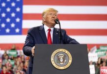 Trump SLAMS Foreign Leader—Cuts Funding! Man speaks at podium with U.S. flag background.