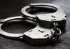 Close-up of metal handcuffs on a dark surface.