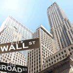 Street signs for Wall Street and Broad Street with skyscrapers in the background