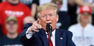 Man in suit pointing, speaking at a rally.