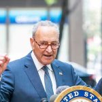 Schumer Meltdown—Dems Erupt, Chaos Unleashed Man in suit and glasses speaks passionately at podium.