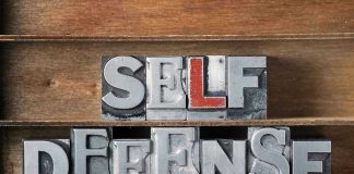 Metallic block letters spelling SELF DEFENSE on wooden shelves.