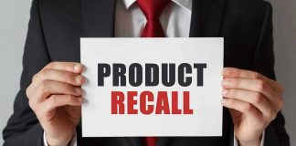 Product Recall sign held by person in suit.