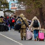 Trump SLAMS Refugee Door – Except For One Nation Group of people carrying luggage walking along a road with a soldier