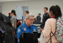 Real ID Takeover Triggers TSA Surveillance Nightmare TSA agent checks passengers documents at airport security.