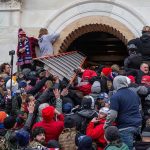 Large crowd storming the entrance of a building.