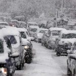 Traffic jam with cars covered in heavy snow during a snowstorm