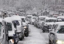 Dual Snow Storms COLLIDE – 45 Million Americans Impacted Traffic jam with cars covered in heavy snow during a snowstorm