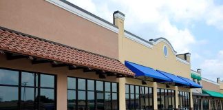 Exterior view of a commercial building with blue awnings and large glass windows
