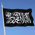 Black flag featuring Arabic script against a blue sky