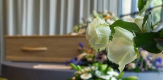 White roses in front of a casket.