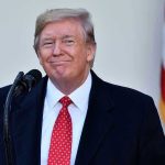 Man in suit and tie speaking at podium.