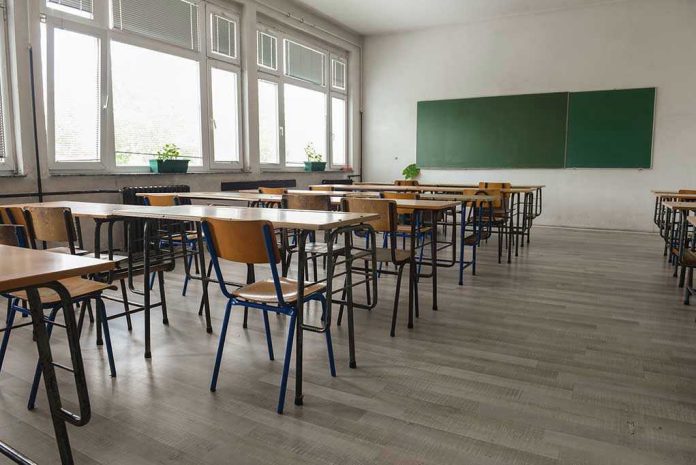 487861393 Empty classroom with desks, chairs, windows, and chalkboard.