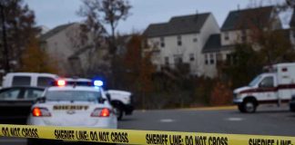 Gunman Fires 70 SHOTS – Kills Woman! Sheriff line tape blocking scene with police and ambulance.
