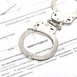 White House Terror Plot Chaos – See His Excuse! Handcuffs on top of an arrest warrant document.