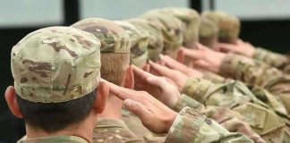 National Guardsman GUNS DOWN Colleague After He Saw THIS! Soldiers in uniform saluting, American flag patch visible.