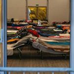 85,000 Kids Missing – Astonishing Audio Captured! Interior view of a temporary shelter with rows of beds.
