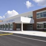 Graduation Chaos – Shooter GUNS-DOWN Ceremony! Modern school building with large windows and a clear sky