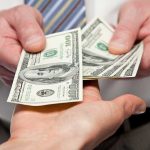 Trump Unveils The NEW $100 Bill! Two hands exchanging cash bills in a business context