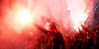 Crowd of protesters holding smoke flares in a city street