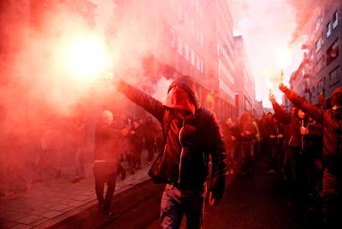 Crowd of protesters holding smoke flares in a city street