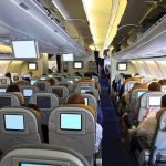 Window Blows Mid-Flight – Passenger CLINGS To Chair! Interior view of an airplane with passengers seated and using in-flight entertainment screens