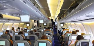 Window Blows Mid-Flight – Passenger CLINGS To Chair! Interior view of an airplane with passengers seated and using in-flight entertainment screens