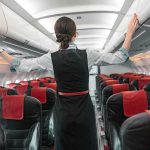Flight attendant checks overhead bins in empty airplane cabin