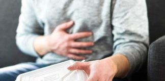 Person holding stomach with takeout container on lap