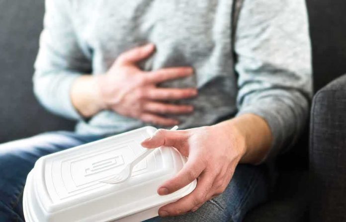 Person holding stomach with takeout container on lap