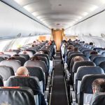 Airplane cabin with passengers seated in rows