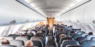 Airplane cabin with passengers seated in rows