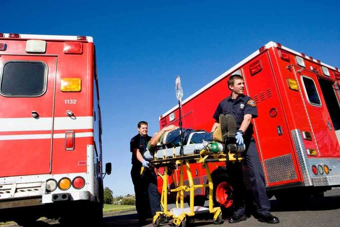 shutterstock_1277231398 Paramedics move a patient on a stretcher between red ambulances