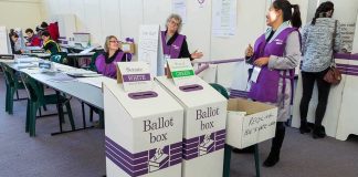 Election workers near ballot boxes in a polling station