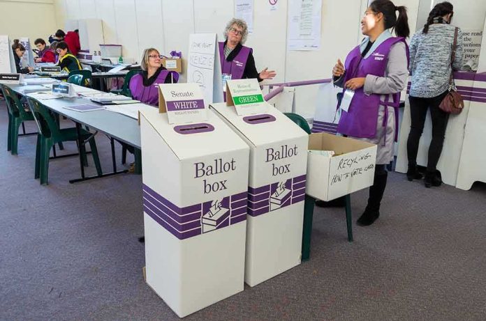 shutterstock_446230945 Election workers near ballot boxes in a polling station