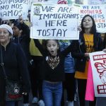 Protesters march holding signs and banners