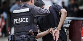 Police officer escorting handcuffed man to a vehicle